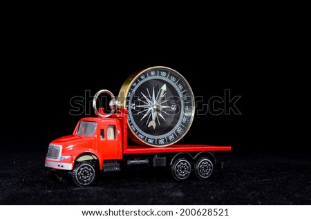 Orientation Transportation Concept Compass on a Red Toy Truck over Black Background