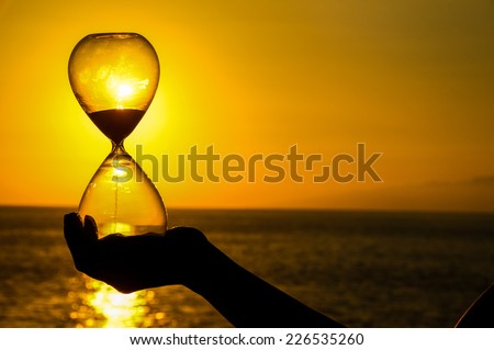Time Concept Hourglass and Sun Setting on the Atlantic Ocean