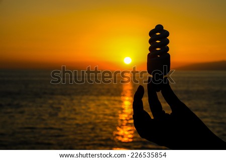 Energy Concept Light Bulb and Sun Setting on the Atlantic Ocean