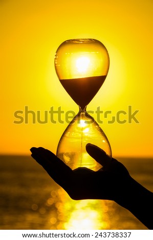 Time Concept Hourglass and Sun Setting on the Atlantic Ocean