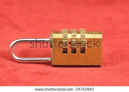 Brass yellow gold combination lock on a red background