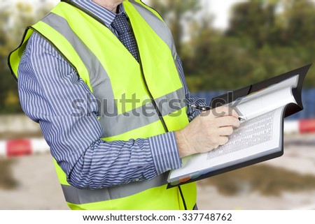 Building surveyor in hi vis checking data in site folder