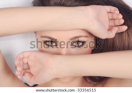 The beautiful girl with an attractive look covers the face with hands