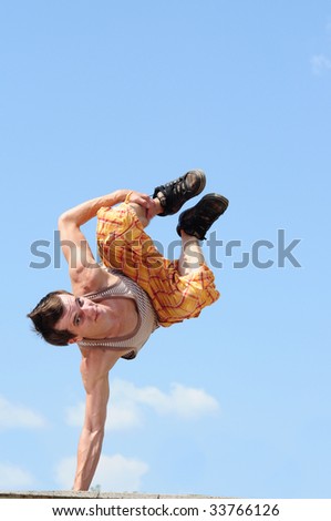 breakdance style dancer doing freeze position in the sky