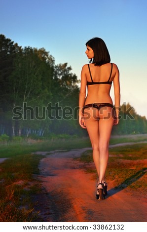 beautiful sexual woman goes on road against the nature