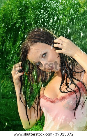 The young nice woman relaxing under a summer rain