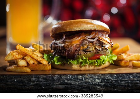 Big burger with fries on the wooden table