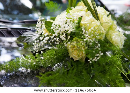bunch of yellow roses as bouquet fixed on a black car bonnet or also called cowl