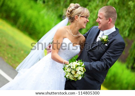 BRIDE AND GROOM LAUGHING and looking to each other while holding the yellow roses bouquet