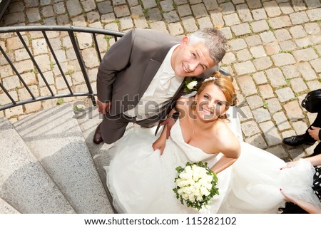 Wedding couple corkscrew stairs. Wedding couple is staying on corkscrew stairs and are looking up, while the bride is holding the bouquet.
