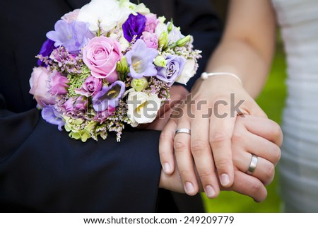 nice couple are showing her hands close p directly after the wedding with their purple roses bridal boquet