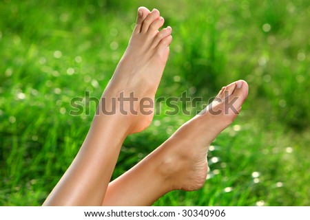 Perfect Feet in the sun with shaved legs on a meadow of a young sexy woman or girl