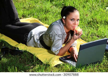 business woman or student lays down on a meadow and uses her wireless network connection with laptop to surf in the www