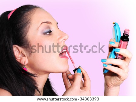 dark haired beautiful Girl applying glamorous blush with makeup lipstick and looking in compact mirror
