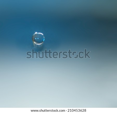 Water drop or clear bubble falling into water surface. Background theme.