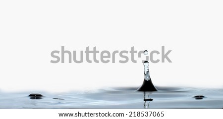 Water drop or bubble falling into water surface and making a crown. Splash background.