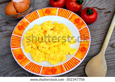 Scrambled eggs with brown egg shells and tomatoes