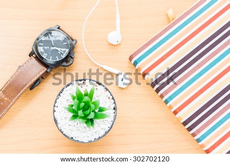 Cactus placed on a wooden table with a book and put a beautiful composition. And a clock with headphones beautiful place.