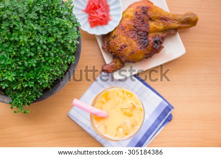 Cold tea in a glass with grilled chicken, cooked hot meal with beautifully laid.