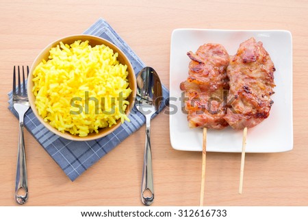 Thai-styled grilled pork. It\'s among most popular street foods in Thailand. With yellow rice eaten together.