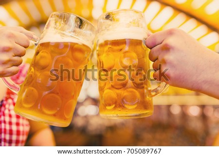 Two hands clinking beer glasses in octoberfest tent