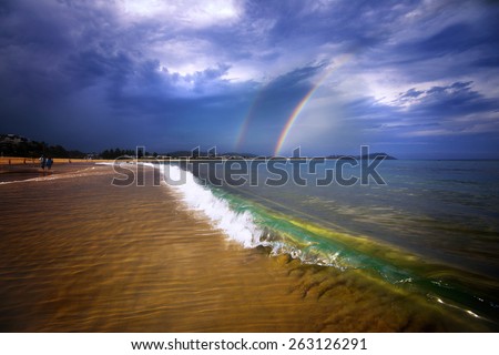 Rainbow in a storm with beautiful waves on the beach