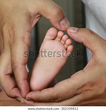newborn baby feet on father hands, shape like a lovely heart