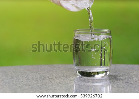 Pouring pure water from bottle on table