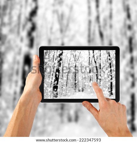 tablet ipades computer in hand on the winter forest backgrounds.