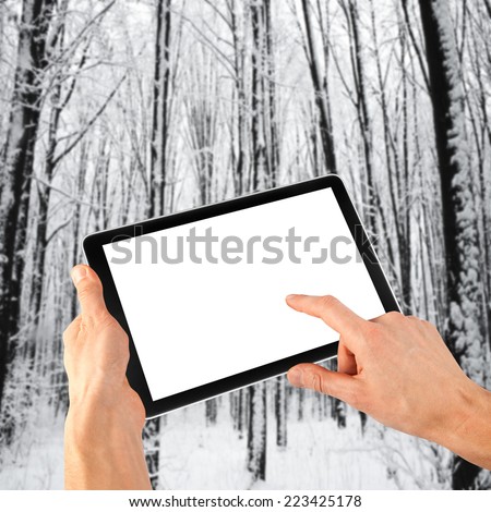 tablet ipades computer in hand on the winter forest backgrounds.