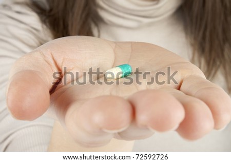 Woman holds a pill in a hand