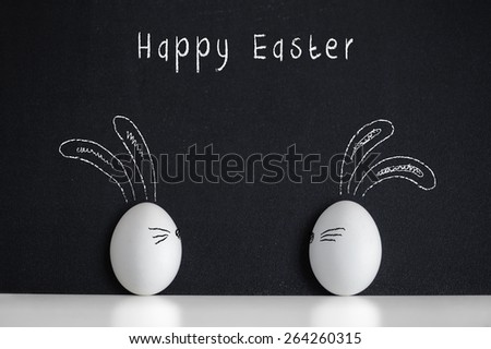 Easter eggs witn painted rabbits on the black chalkboard
