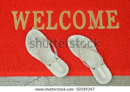 A Pair Of White Slippers On A Welcome Mat