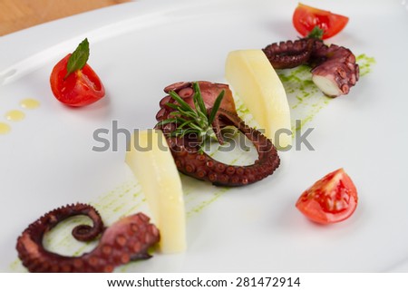 Sliced octopus served with potatoes and tomatoes