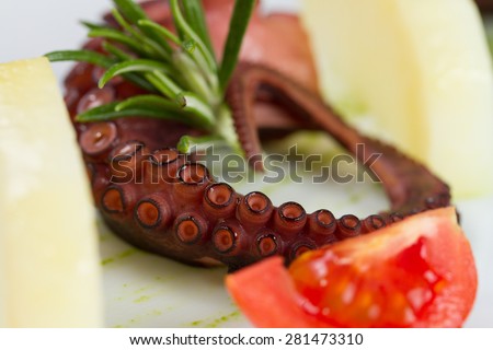 Closeup of sliced octopus served with potatoes and tomatoes