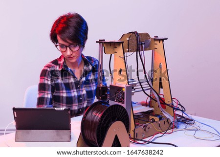 Young female designer engineer using a 3D printer in the laboratory and studying a product prototype, technology and innovation concept