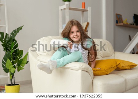 Child with a cast on a broken wrist or arm smiling and having fun on a couch. Positive attitude, recovery and kid concept.