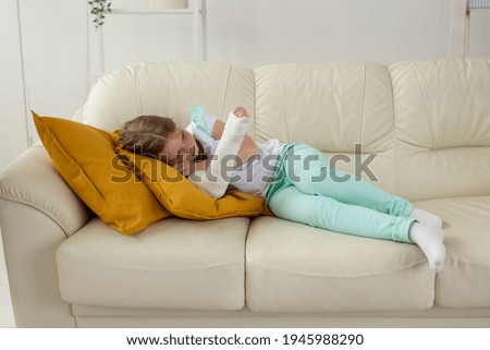 Child with a cast on a broken wrist or arm lying on a couch. Recovery and disease concept.