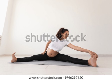 Purposeful pregnant woman exercises during yoga class and relaxes while sitting on a mat on the floor. Concept of physical and mental preparation of the body for childbirth. Place for text