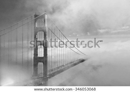 Golden Gate Bridge in black and white with the fog rolling in and the second tower visible in the distance.  Artistic in composition and lighting.