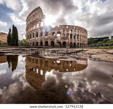 Roman Colosseum in Rome Italy with a reflection on water with the sun shining through the clouds