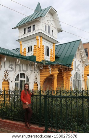Tourist girl. Facade of yellow wooden house (\