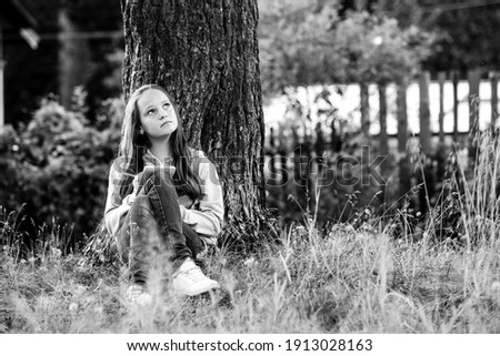 Girl student writing in a dairy notebook while sitting in the park. Black and white photo.