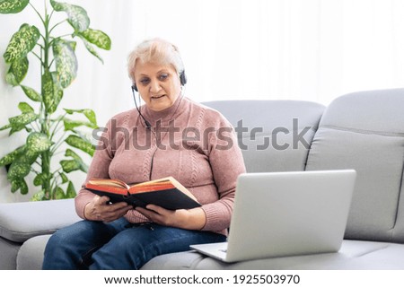 elderly Woman with bible and laptop in front of her connected to online church services durring the covid 19 outbreak