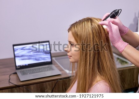 cropped unrecognizable doctor dermatologist diagnoses structure of hair of a young woman using tool trichoscope. Trichology, trichogram, hair concept. side view