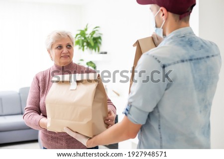 An elderly woman in a medical mask stays at home. Food delivery to the elderly