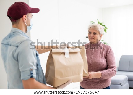 An elderly woman in a medical mask stays at home. Food delivery to the elderly