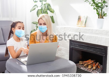 Coronavirus. Mom and daughter wearing protective mask in quarantine. Stay at home, woman working on laptop while taking care of baby. Freelance work. Child make noise, playing and disturb mom