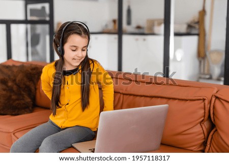 Child online. A little girl uses a laptop video chat to communicate learning while sitting at a laptop at home