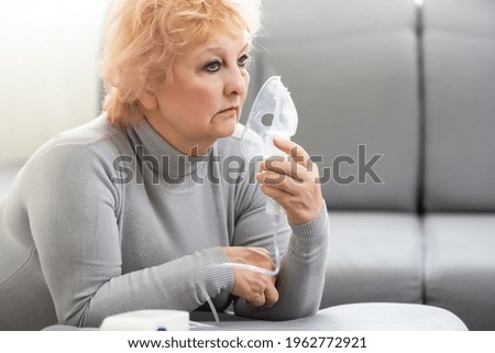 Sick elderly woman making inhalation, elderly woman and nebulizer